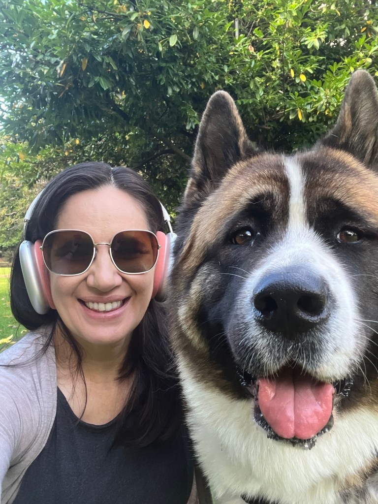 Image of woman and her dog, and American Akita named Bella.  The woman is wearing headphones.